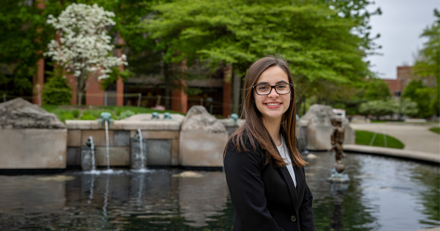 student in front of Frog Baby fountain
