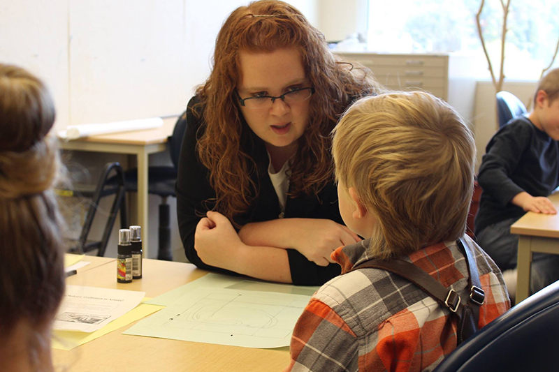 student teacher teaches child student about art