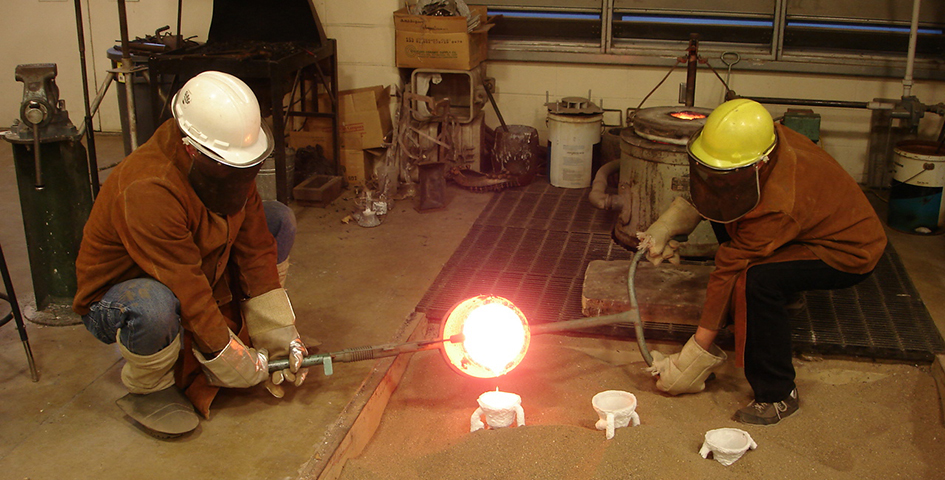 students working with melted metal in a sculpture lab