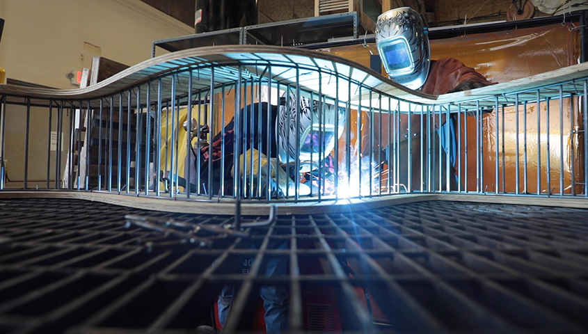 Student and Professor welding a bench structure at iMade