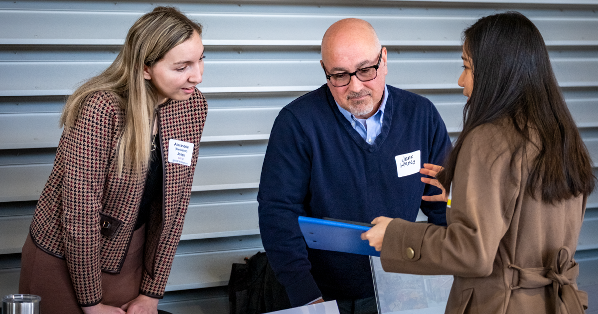 Two employers talk with a student at the Ball State career fair 