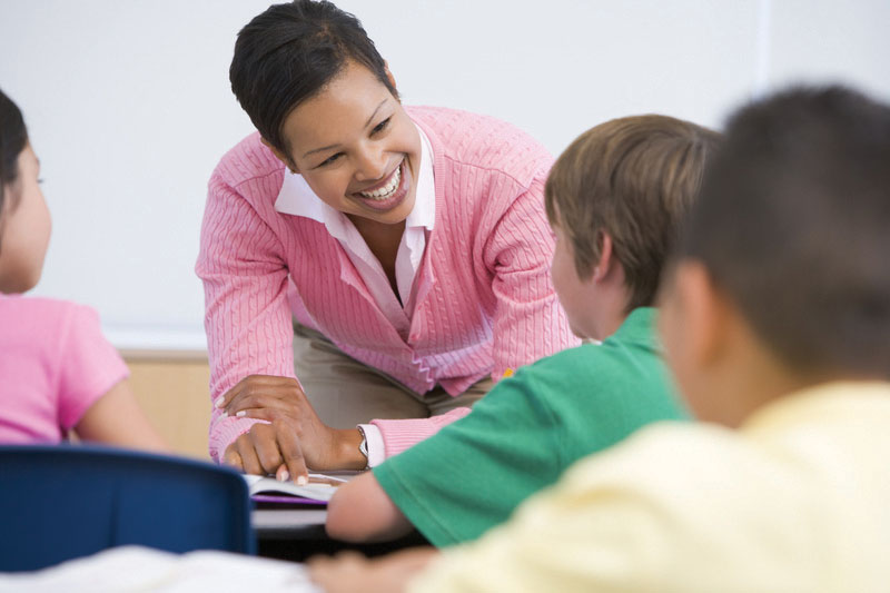 A teacher smiling as she works with a group of students.