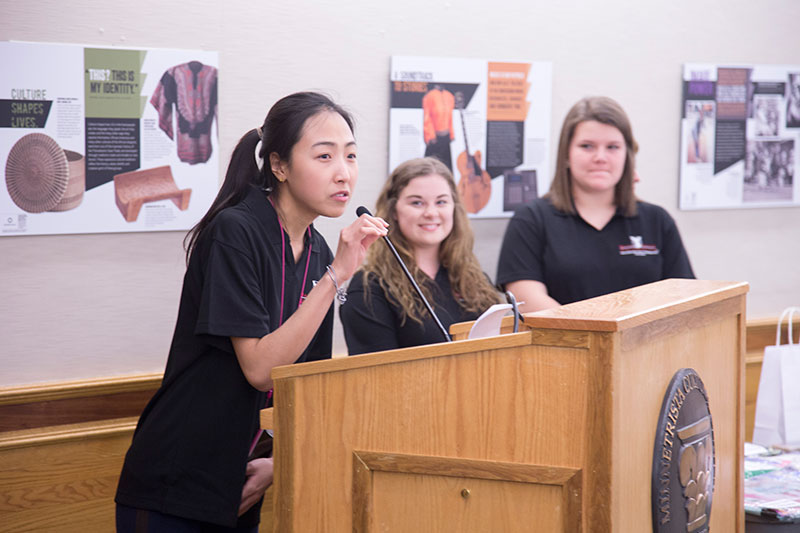 Graduate students standing at a podium giving a presentation.