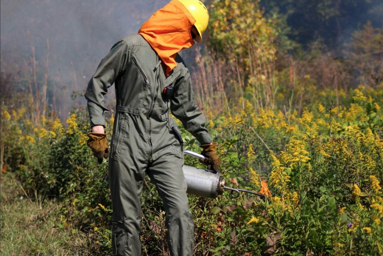 photo of crew member performing a prescribed burn in a prairie at BSU