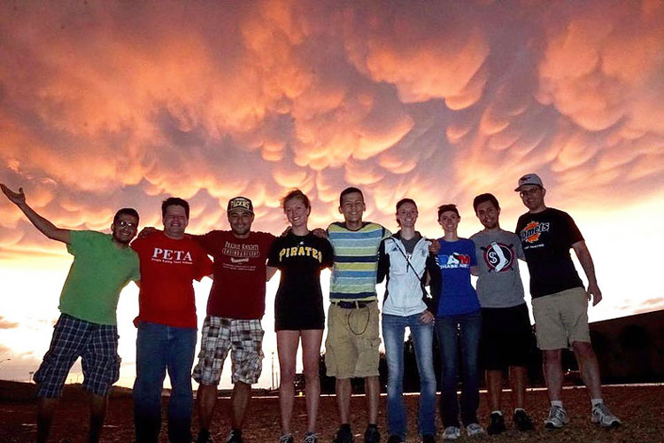 group of students posting in front of a vivid sky