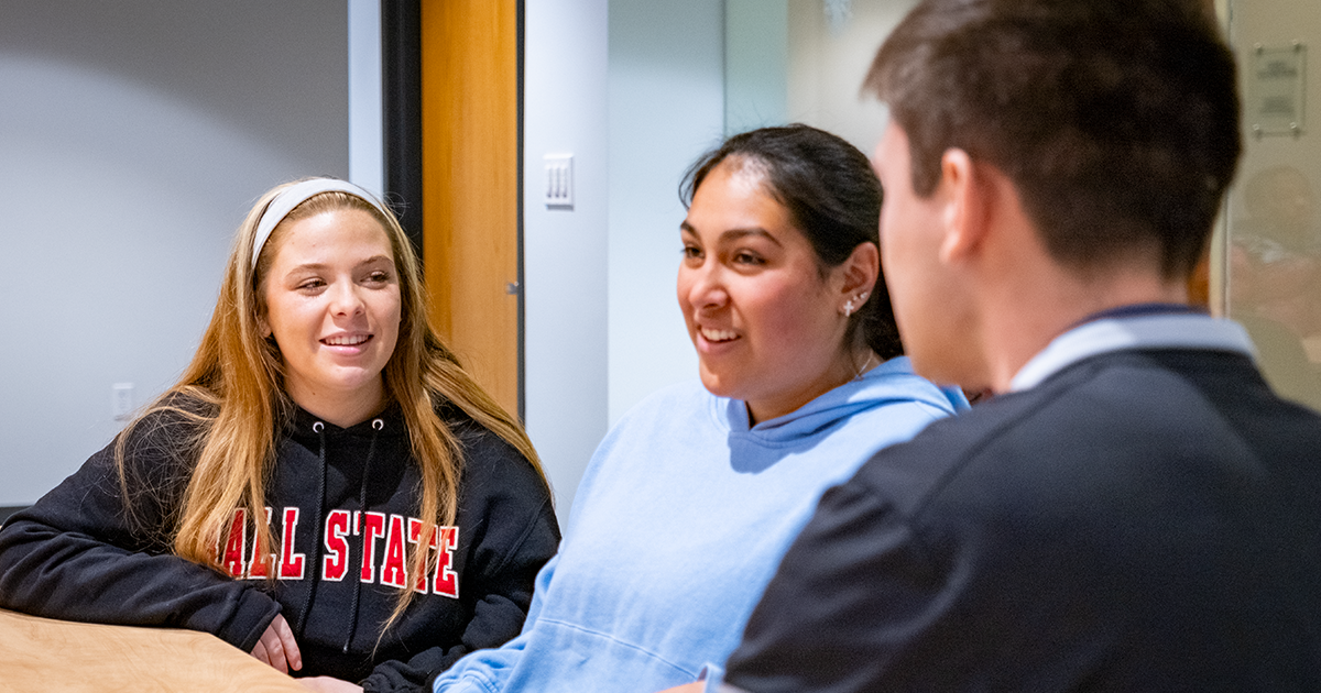 Three Ball State students sitting together discussing a group project 