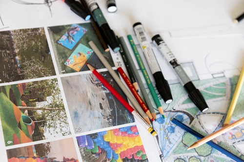 A pile of markers over photos and landcape plans