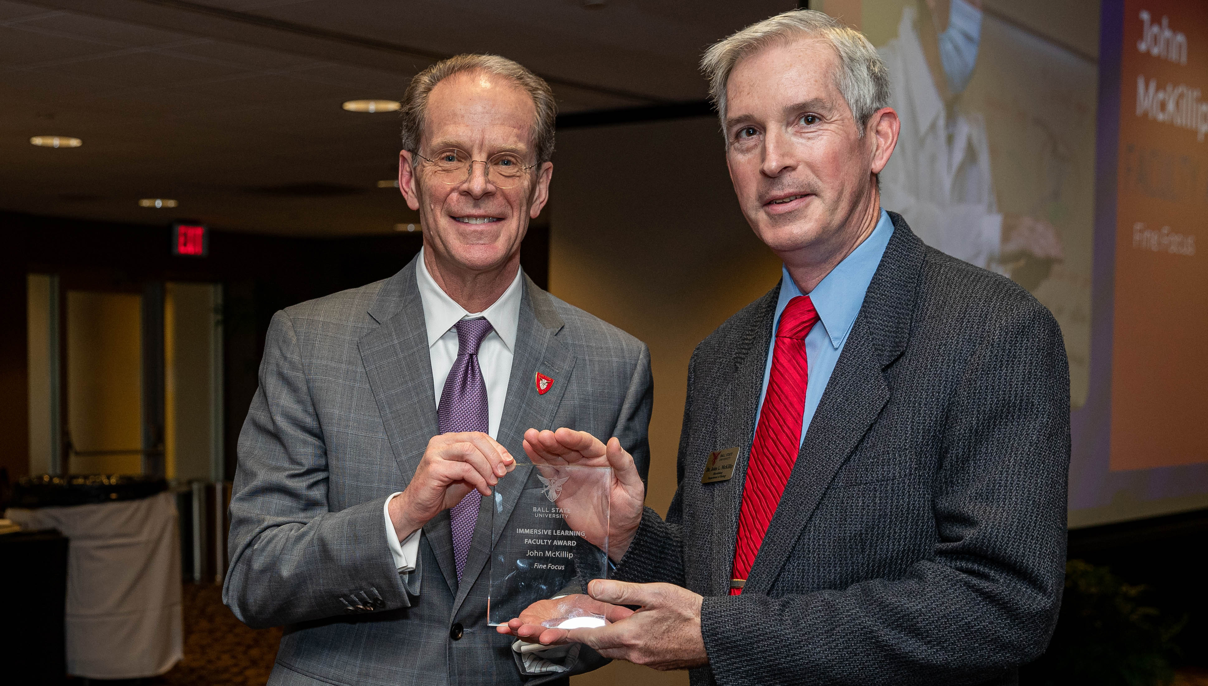 President Mearns and Dr. John McKillip pose together holding a glass award. 