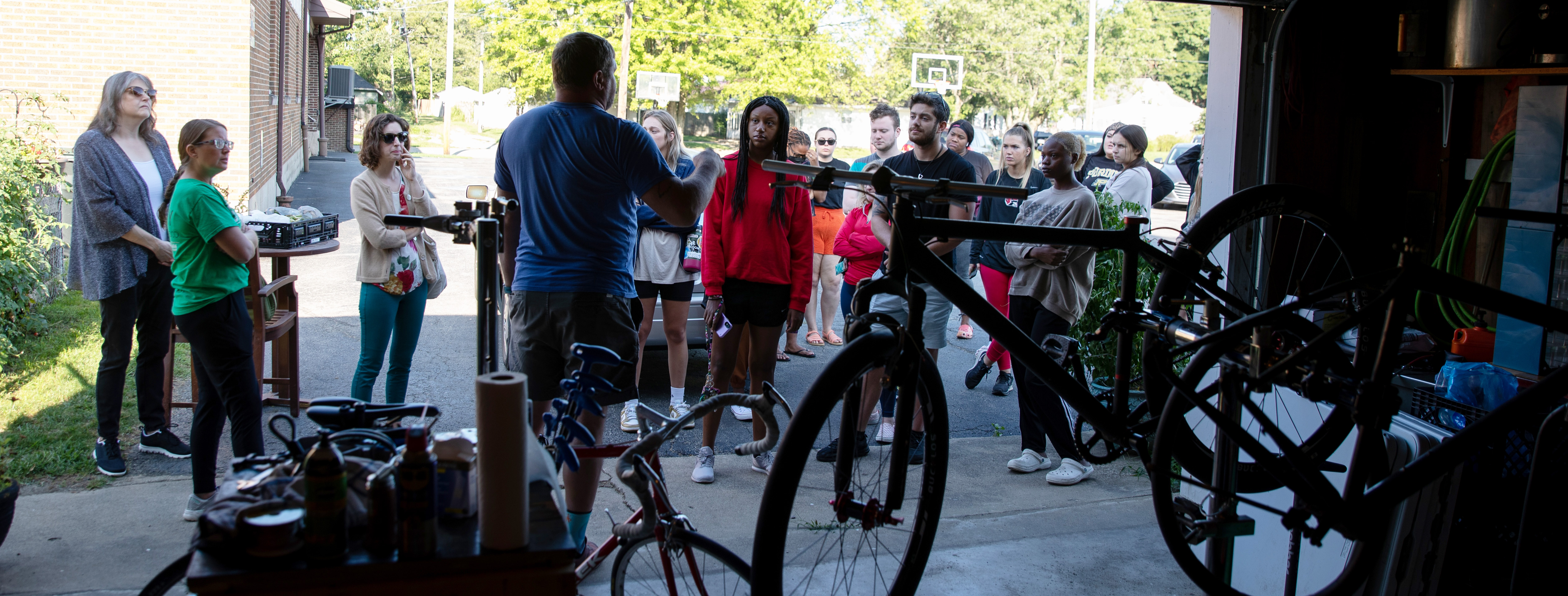 A group of speakers listen to a speaker with bikes in the foreground.