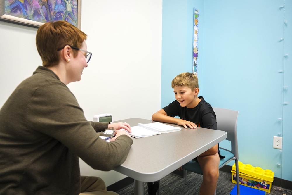 A Teachers College student clinician talks with a child across a table in the Health Professions Building’s Psychoeducational Diagnostic Intervention Clinic.