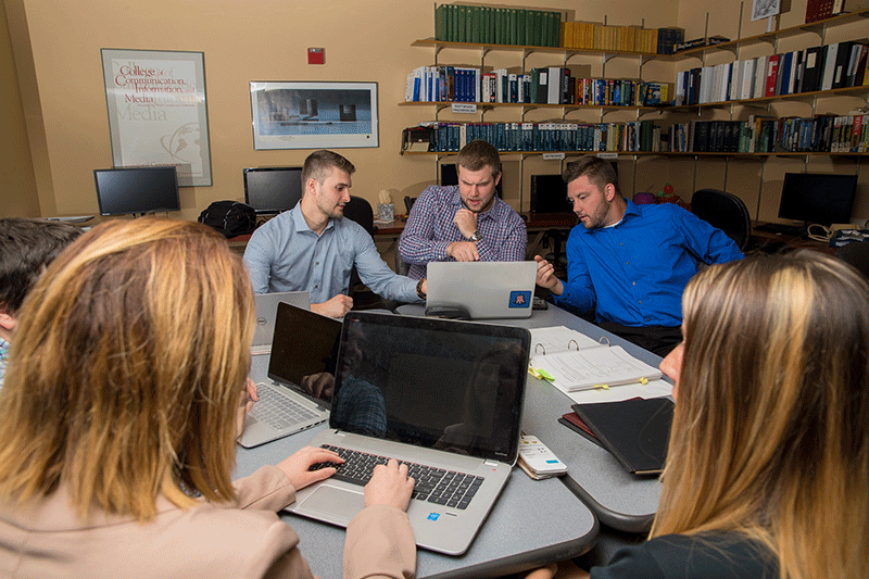 A group of students working together on their laptops.