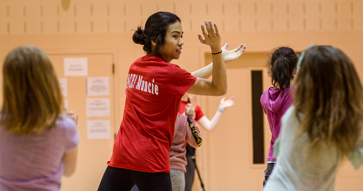 Ball State University student leading a group of kids in a exercise 