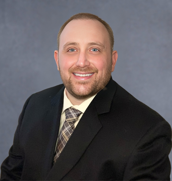 Headshot image of Michael Gambrel with a black suit and gray background