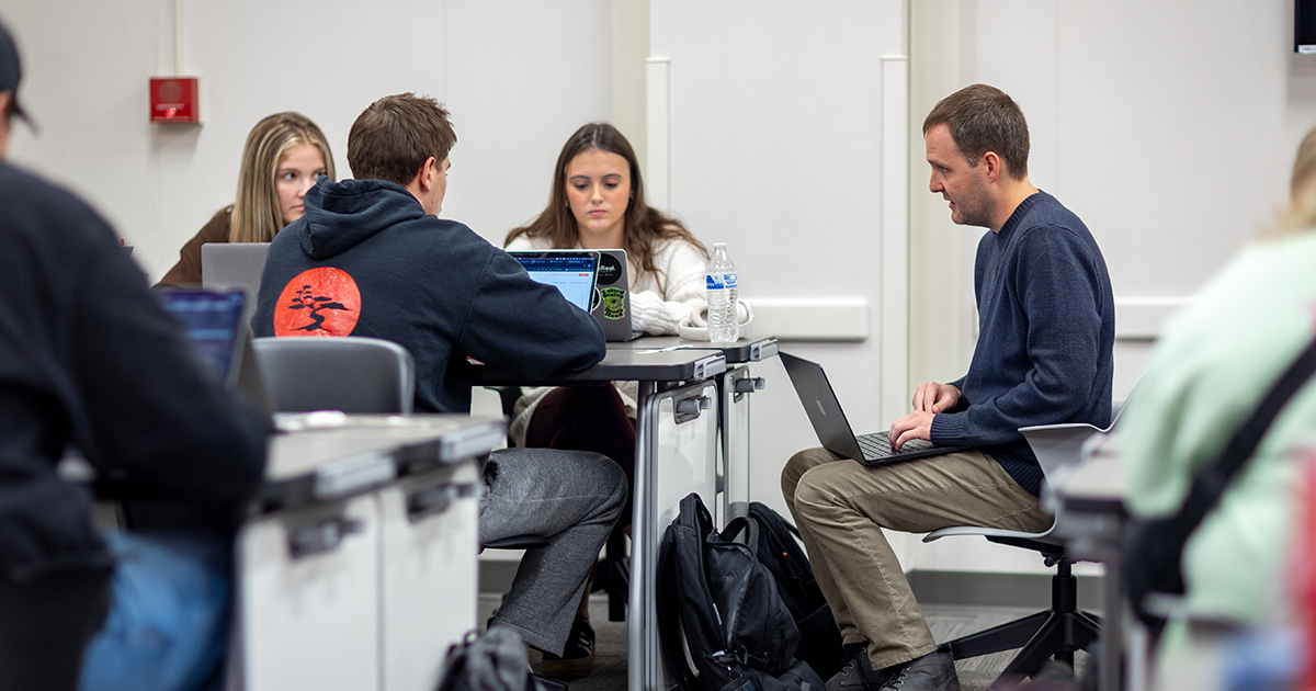 A group of Ball State students sit with a professor to discuss a project 