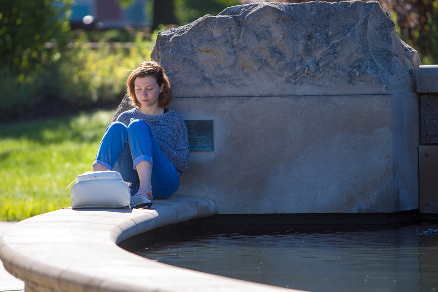 student studying by a fountain