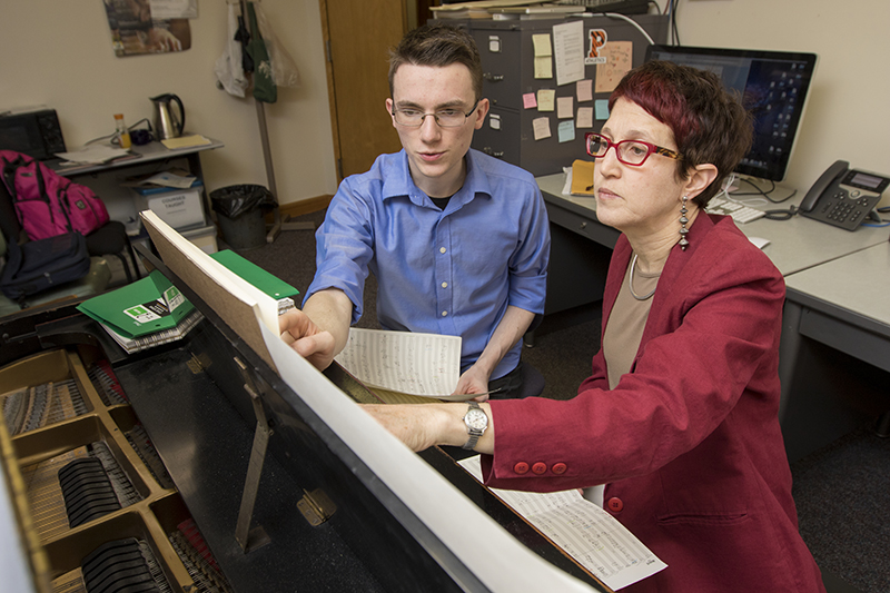 Student and instructor sit at the piano reading music