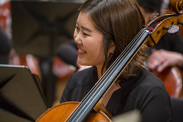 female student playing cello on stage