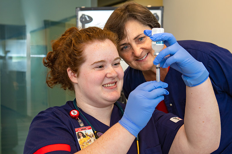 A nursing student works with a professor
