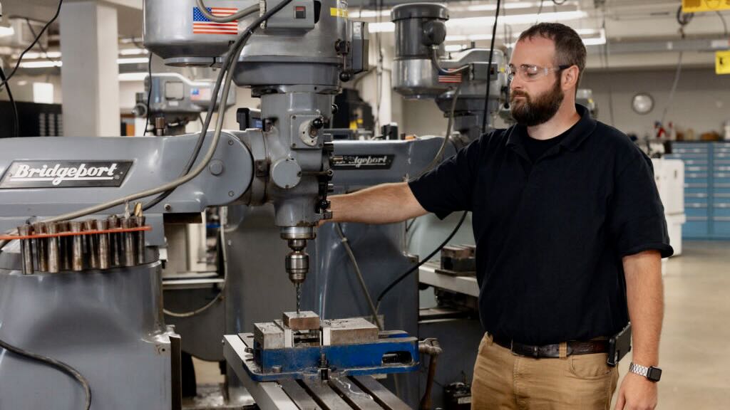 Dalton Foley operating a drill press in a machine shop.