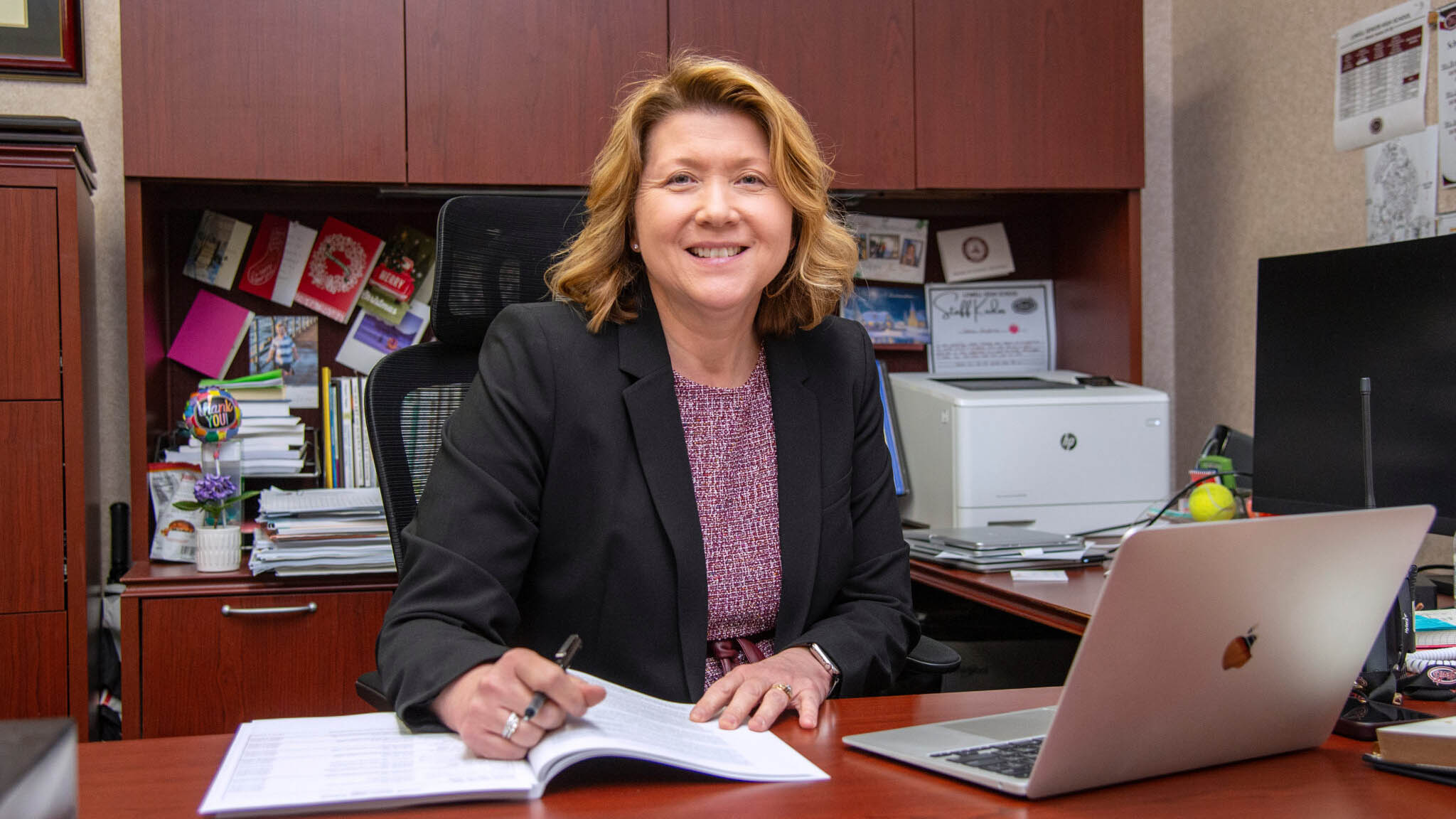 Tammy Daugherty wearing business attire and sitting at a desk smiling