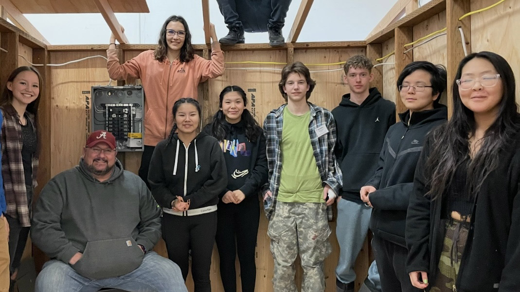Jerry Jones sitting and smiling with students in a mock construction site