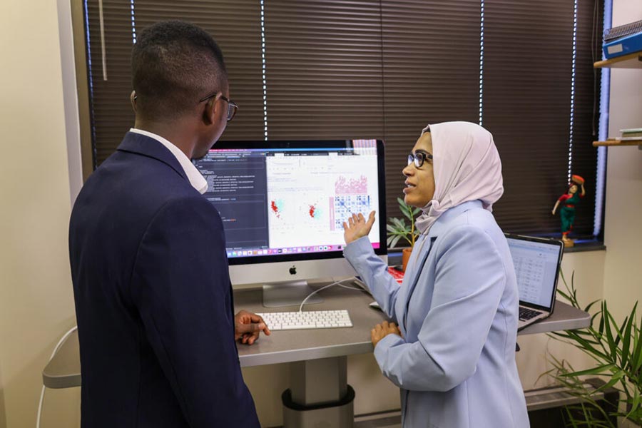 Dr. Munni Begum speaking with a student and pointing at a computer screen