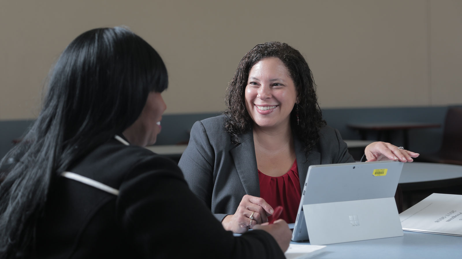 A woman wearing business attire, smiling while seated