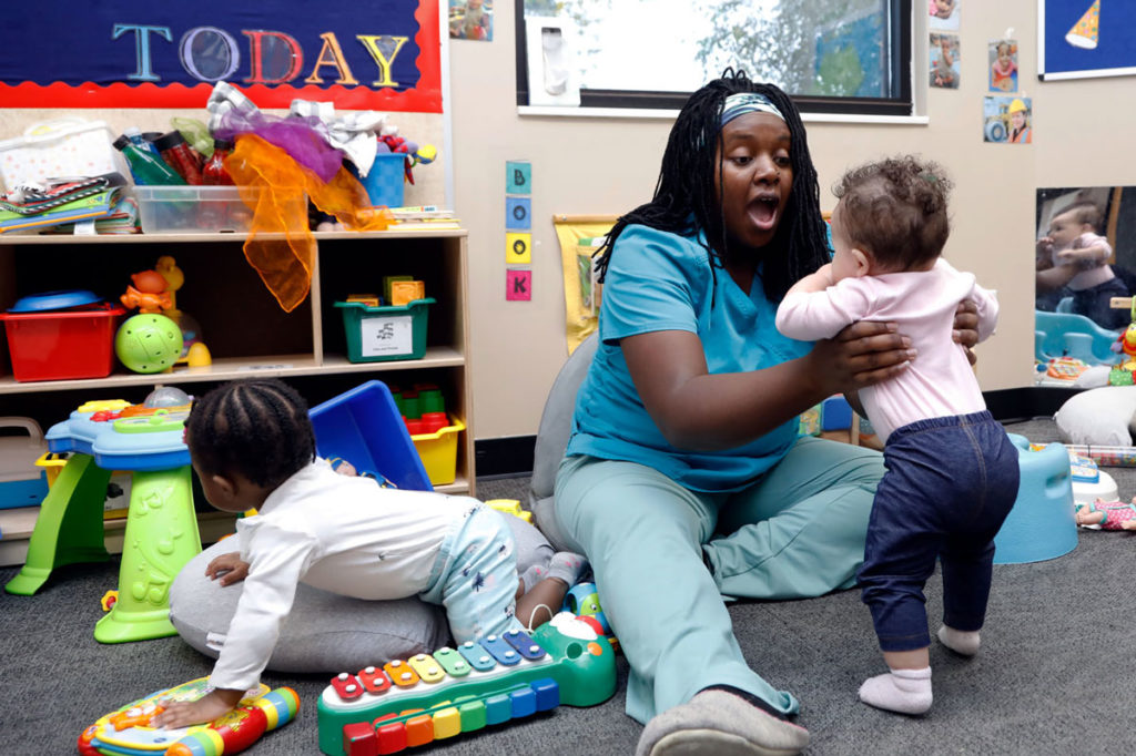 Woman holding a child while speaking in an early childhood classroom