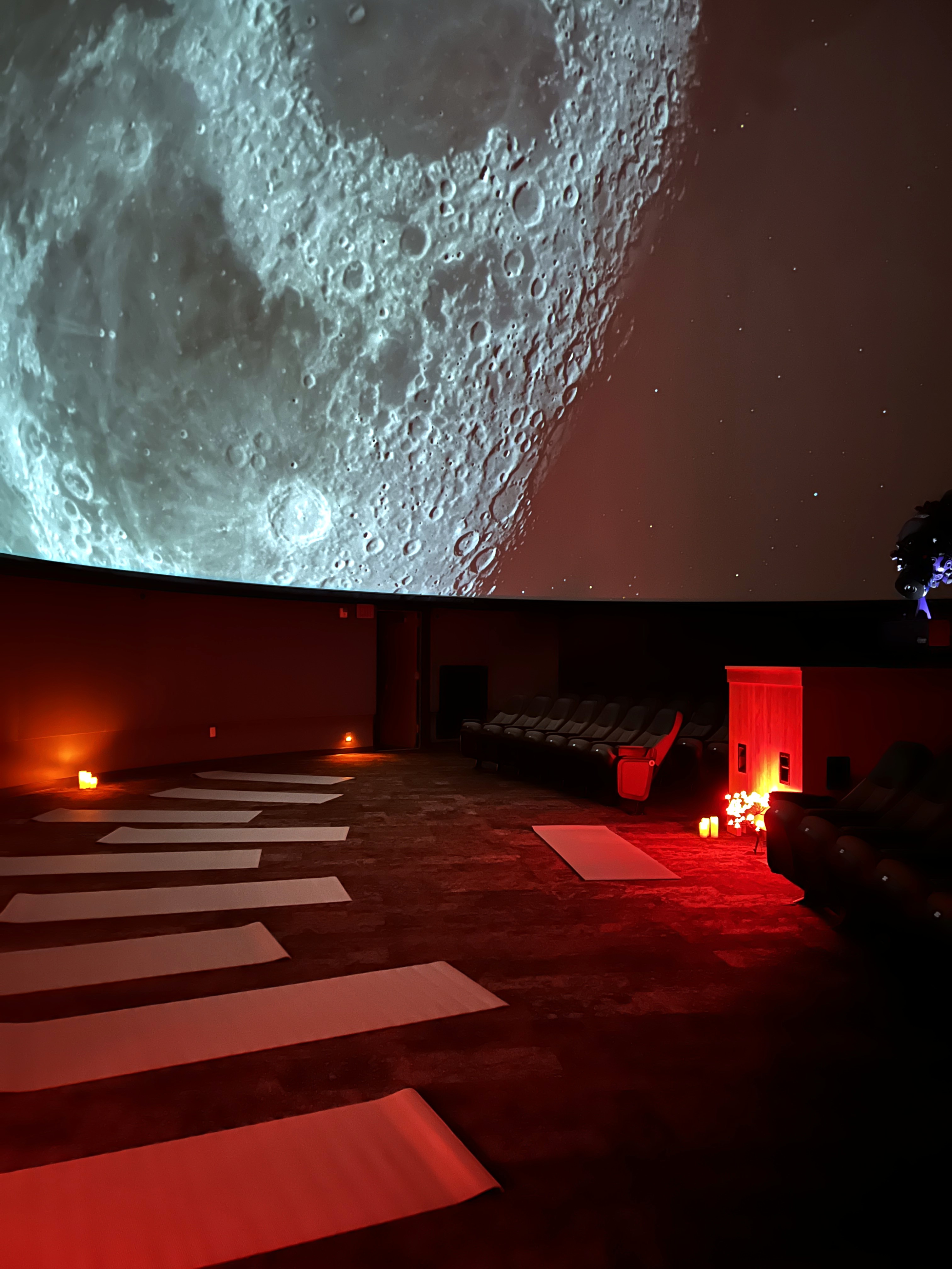 Yoga mats setup in the planetarium with the Moon projected onto the dome.