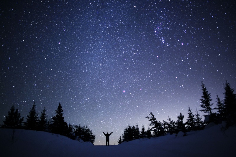 night sky with snowy landscape and a person looking up at it