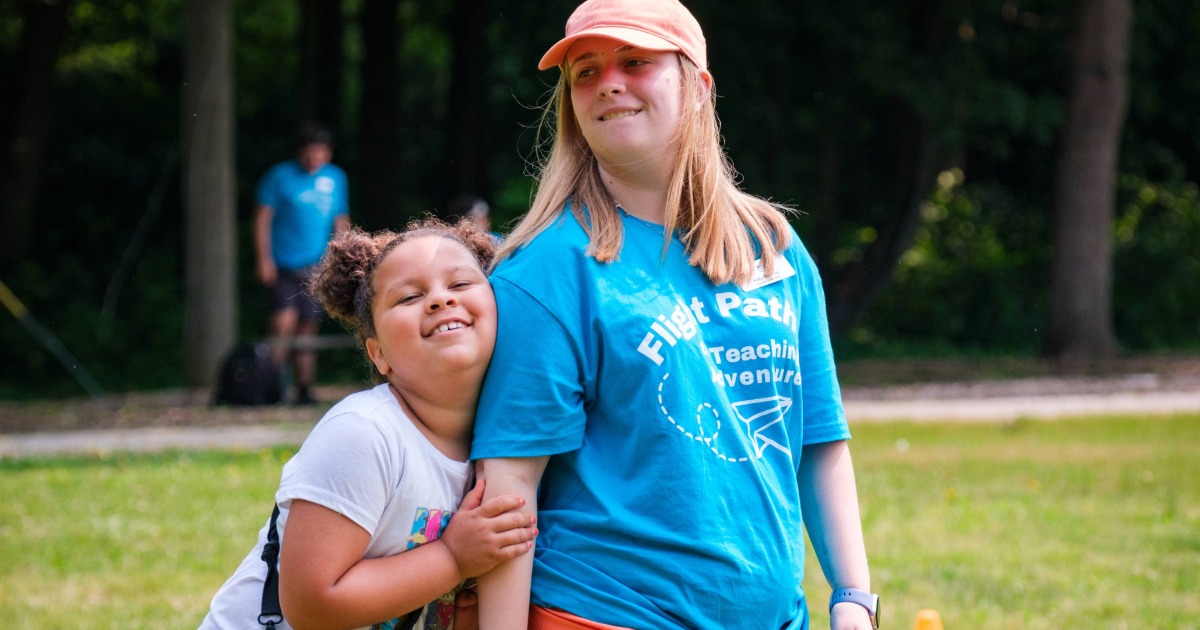 A small kid and a big kid smiling and hugging each other