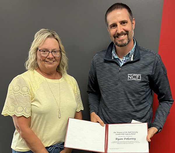 Ball State University employee recognition photo featuring a presenter and award recipient displaying an open certificate folder.