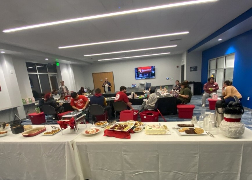 catered food is on a table while students enjoy a party in the background