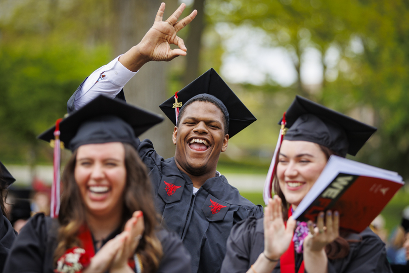 Three students with their graduation cap and gown on