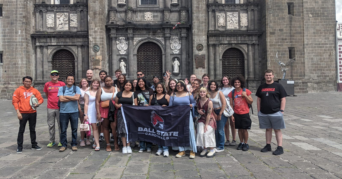 Ball State study abroad students pose for a group photo in front of a gothic-looking building