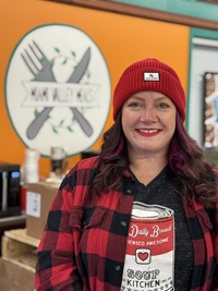 Amanda stands in front of the Miami Valley Meals logo