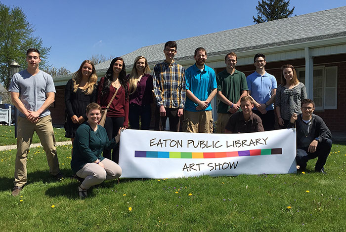Students Holding Art Show Banner