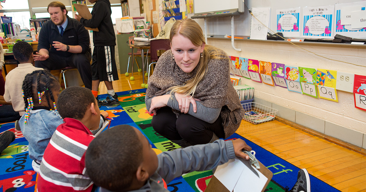 Students sitting on floor with teacher.