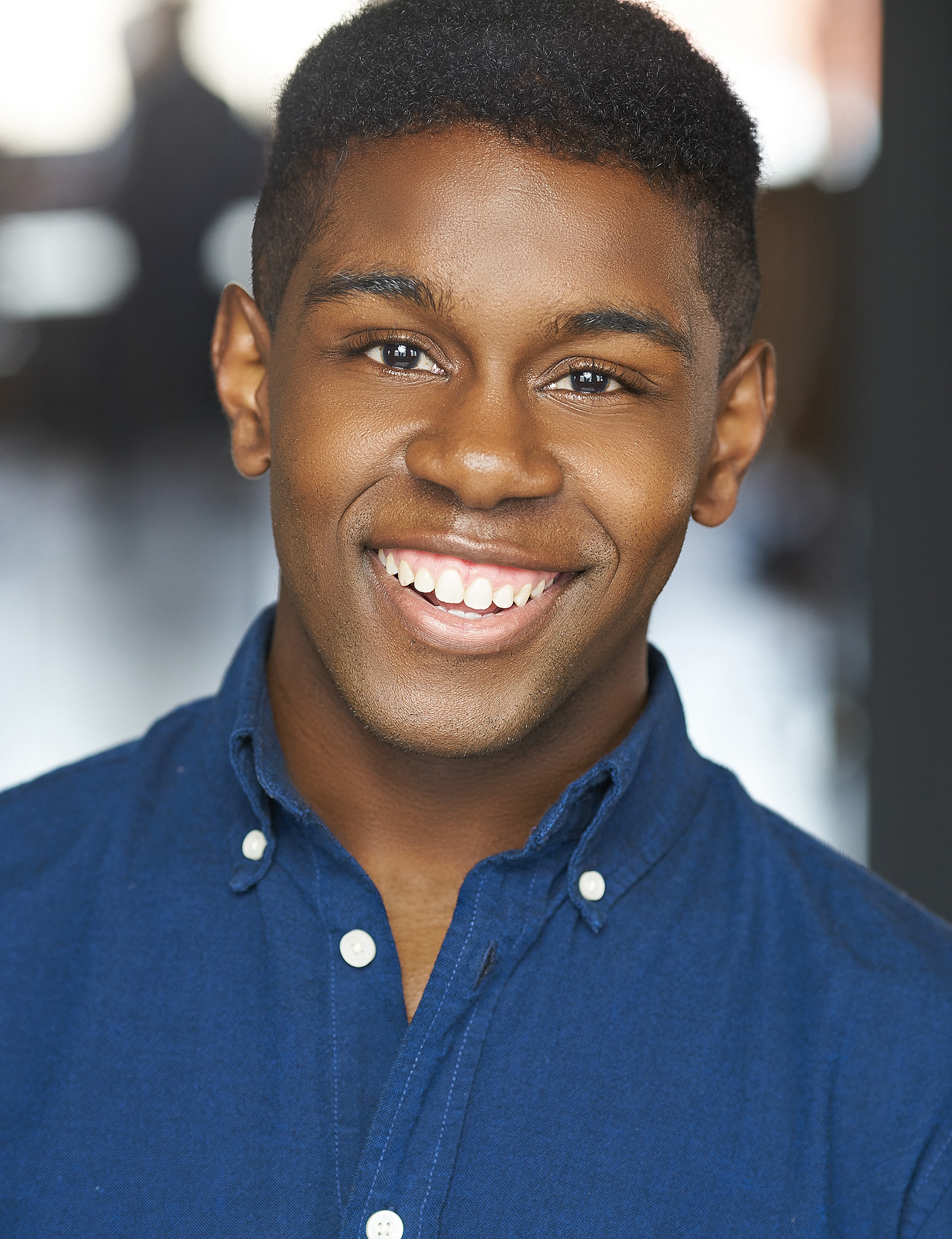 Photo of Evan Duff. A Black/African American Male with short hairstyle and wearing a blue button up shirt.