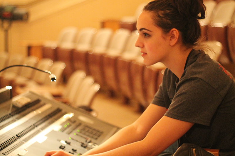 student works the sounds board at a production