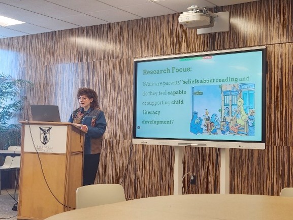Amaya Smith presents research on family reading and child literacy development at a podium.