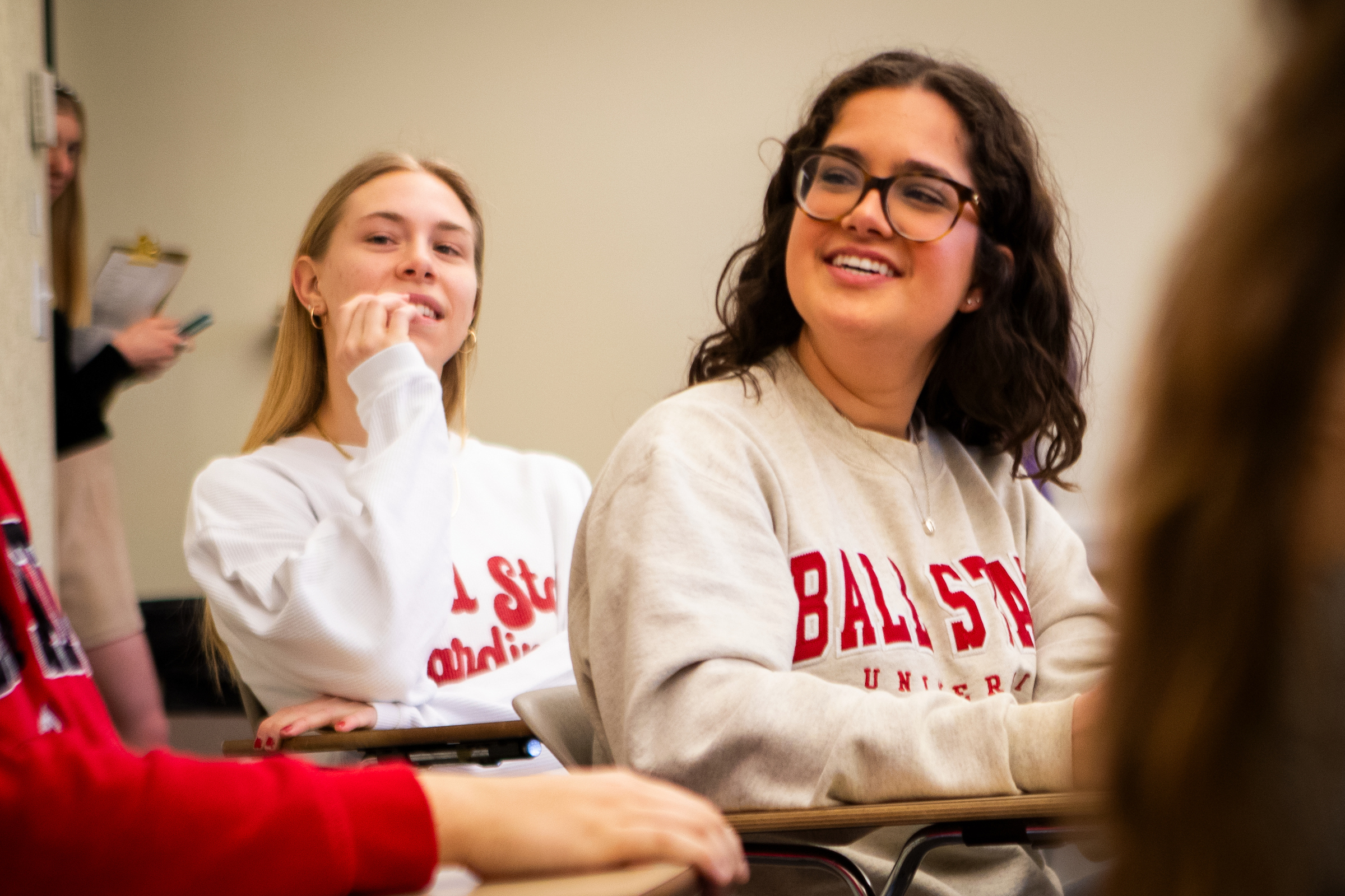 Two female Ball State University students smiling and engaged in a classroom setting.