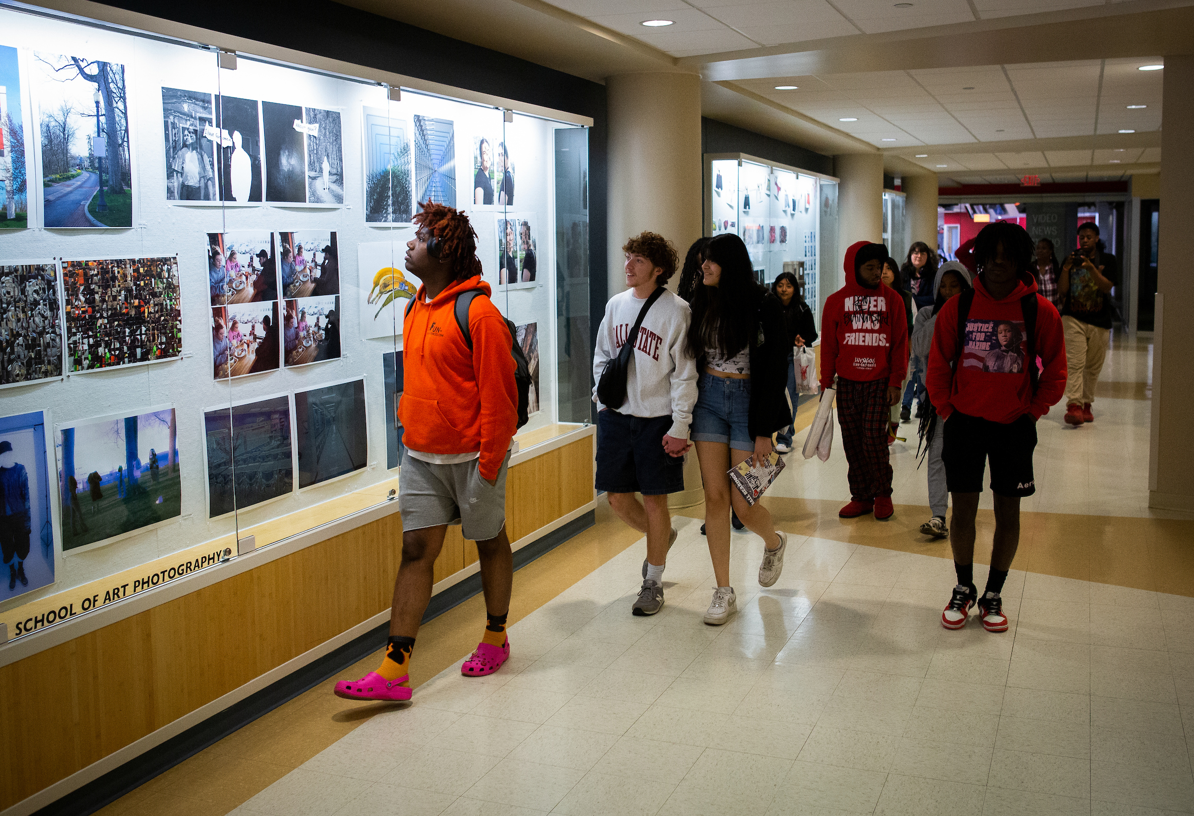 Prospective students walking through the Arts and Journalism Building looking at the artwork showcased in the halls