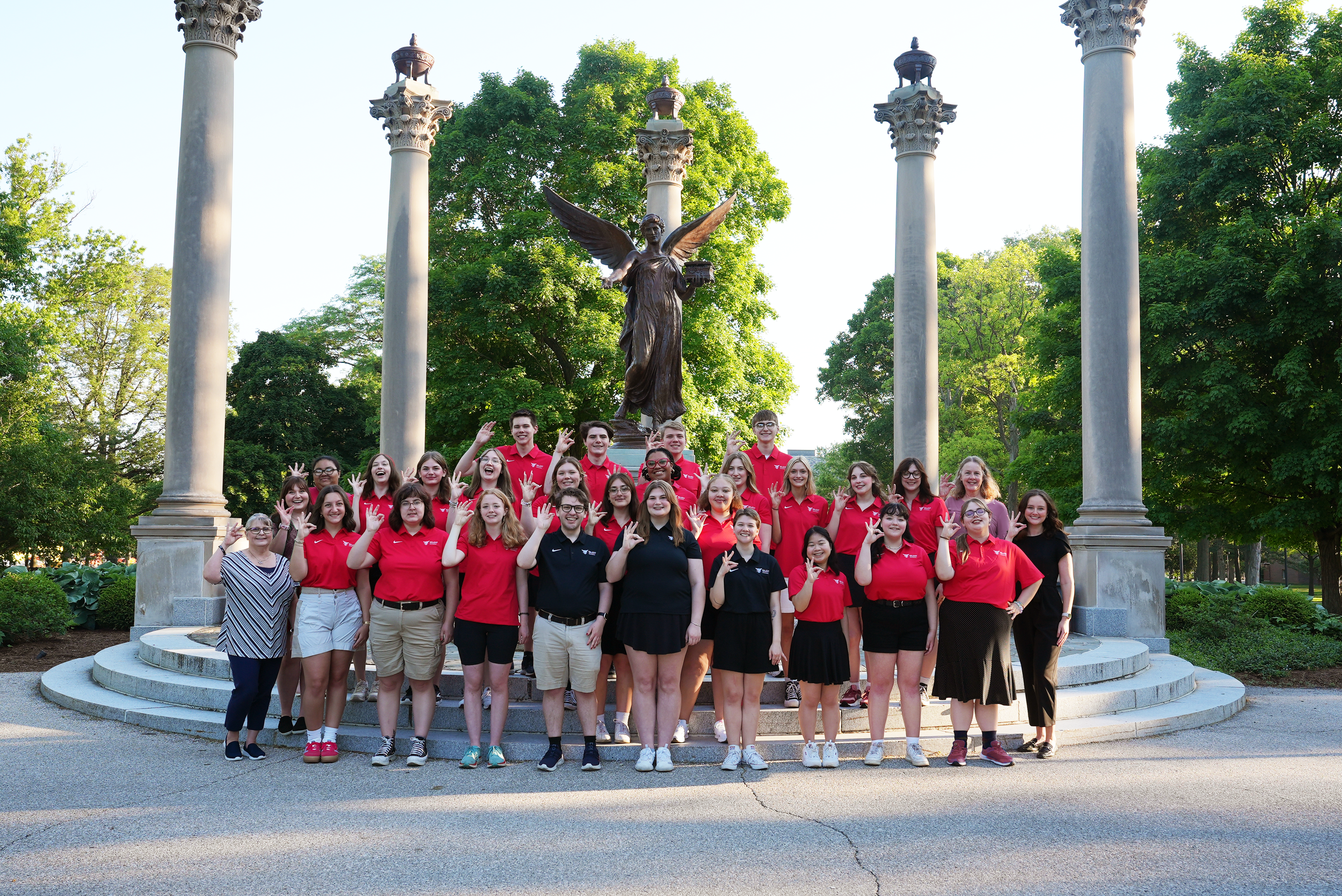 The 2024 Orientation staff at Ball State University poses for a photo on the steps in front of the Beneficence Statue.