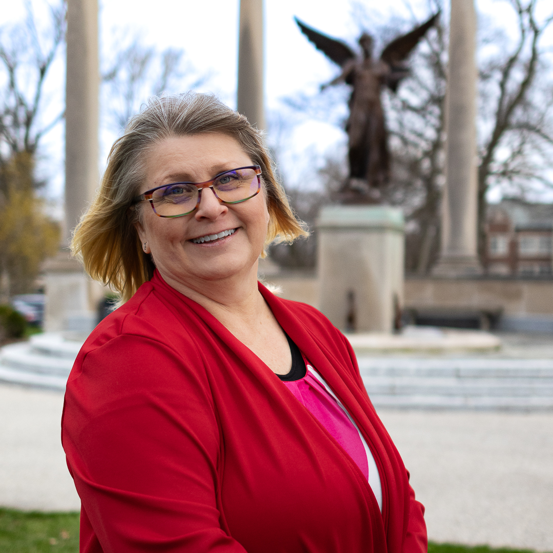 Professional headshot of Andrea Landis with Beneficence Statue blurred in the background.