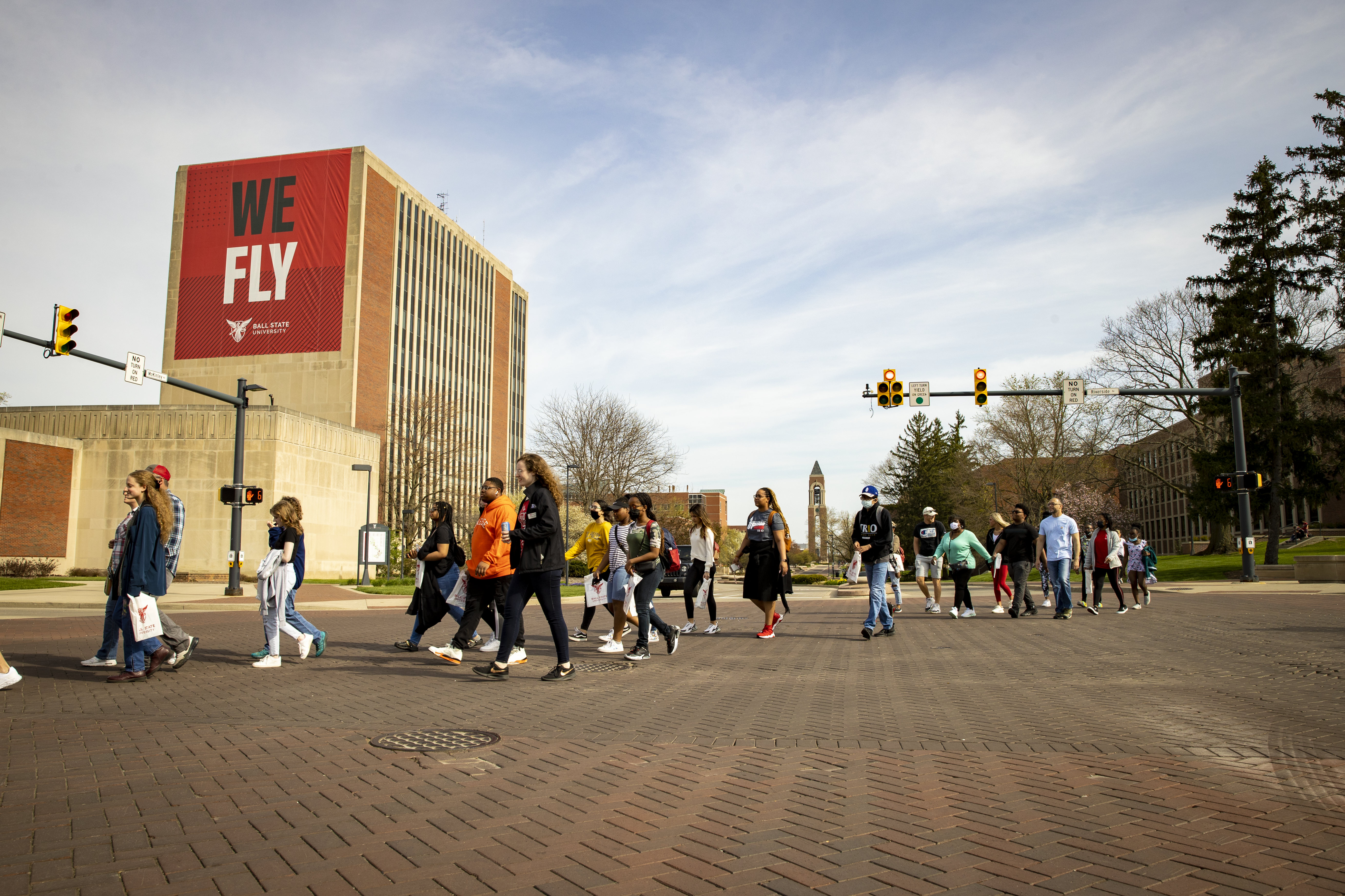 A group of prospective students touring campus and walking through the Scramble Light with the Teacher's College in the background