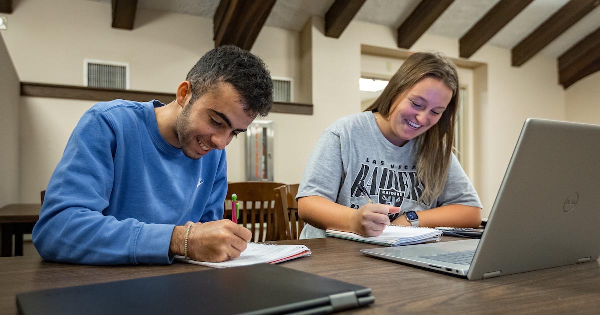 learning center students sitting at a table and writing on notebooks