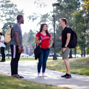 3 people chatting on a paved path in the quad