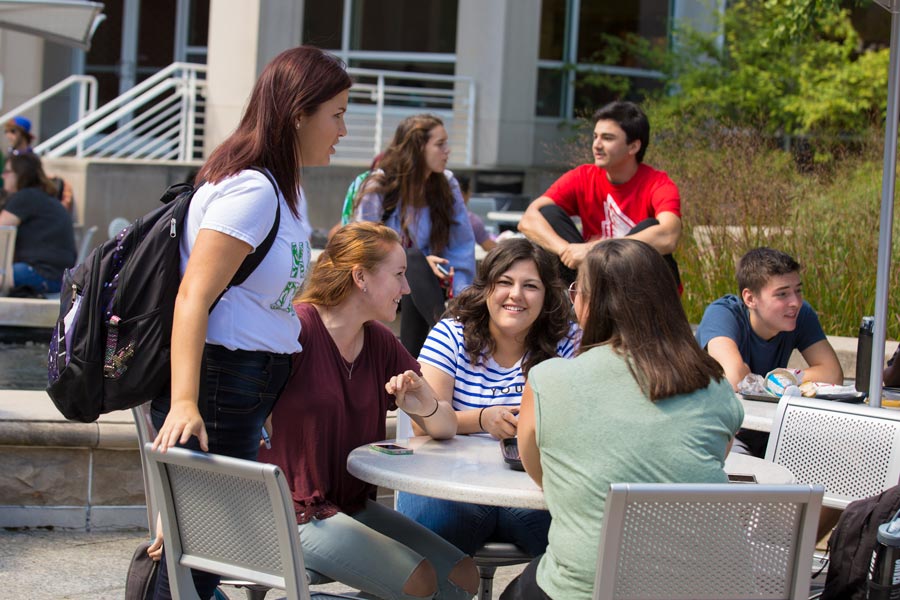 students gathered around a table outside the Atrium