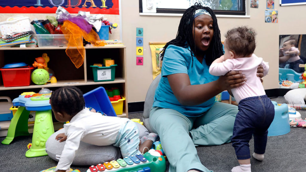 Woman holding a small child in a classroom